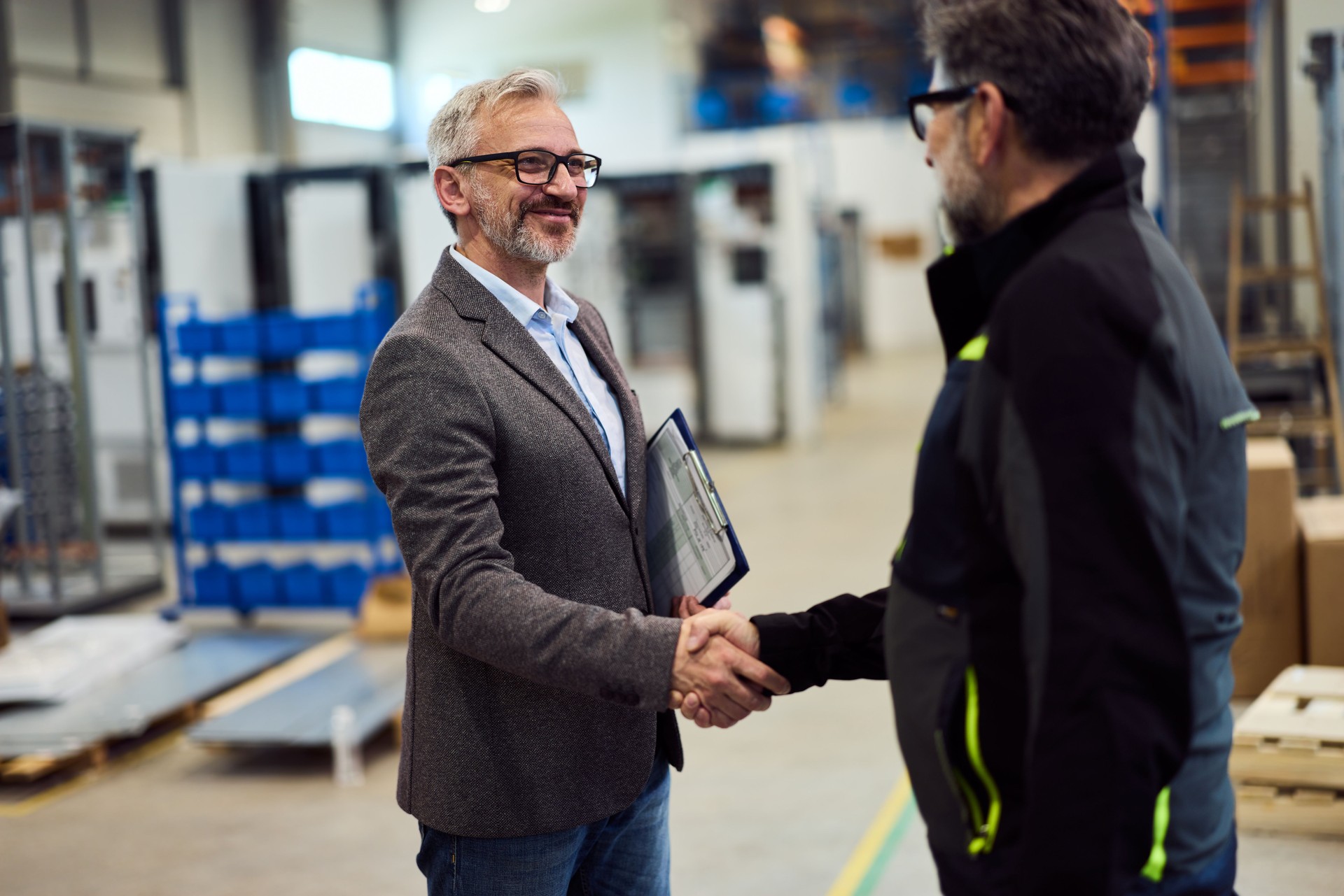 Business Professionals Shaking Hands in a Factory Setting Showing Agreement